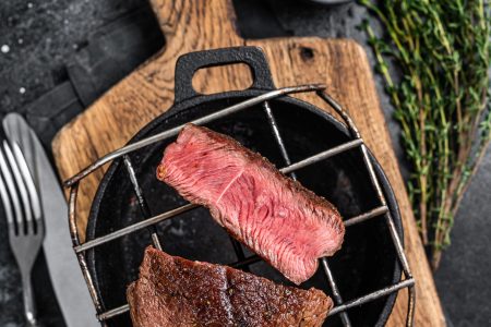 Beef tenderloin steak is grilled on a grill pan. Black background. Top view
